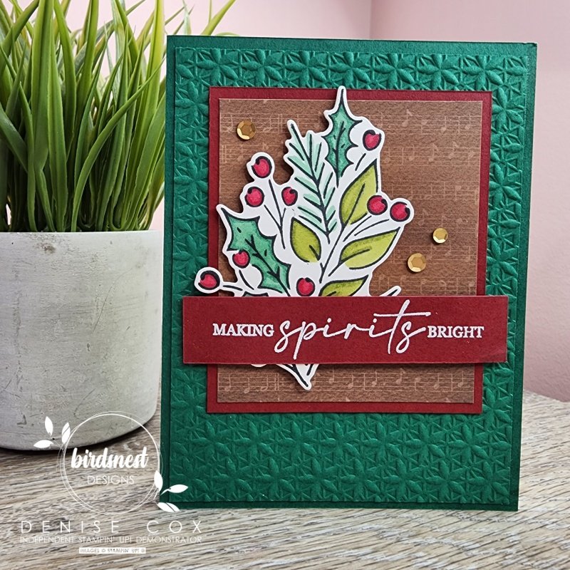 Photo of the front of the Joy of Christmas card displayed standing next to a plant