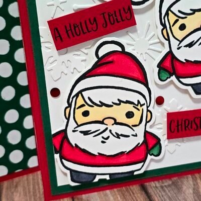 Close-up of a handmade Christmas card featuring a cute Santa from the Festive Friends bundle, with red and green accents, embossed snowflakes, and cheerful holiday sentiments.